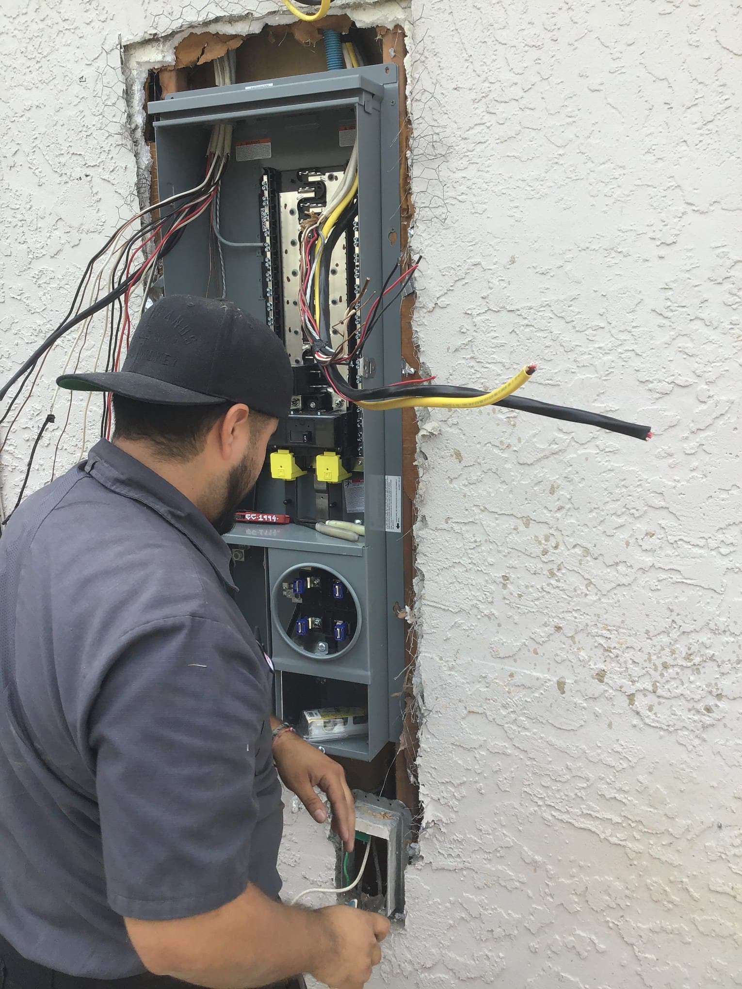 Technician working on wiring inside an exterior electrical panel
