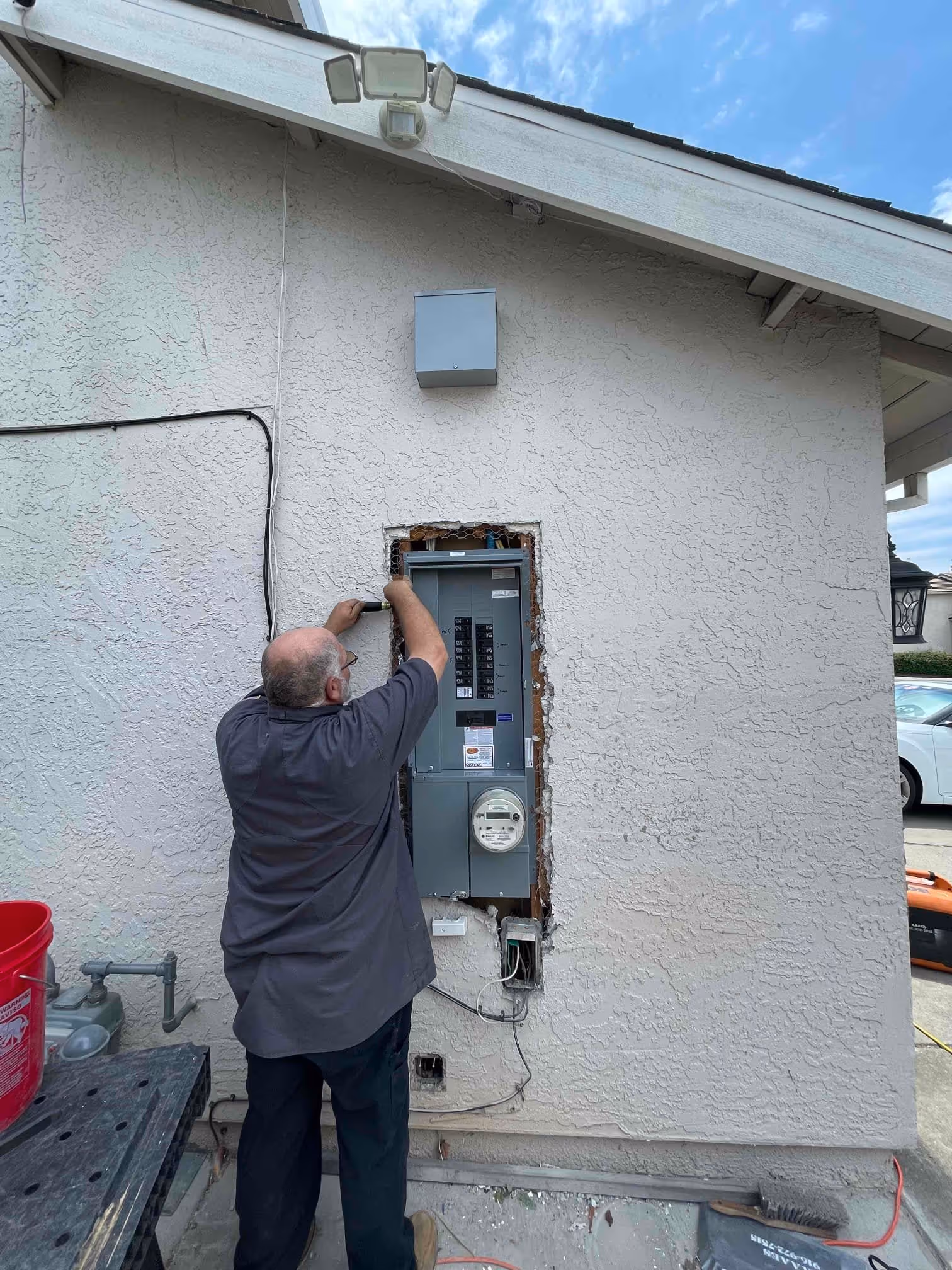 AAA electrician working on an exterior electrical panel